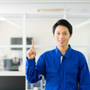 作業服で指を指している男性。